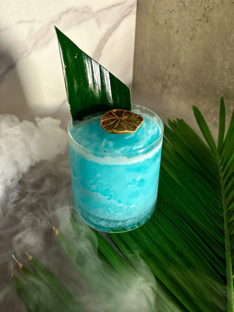 A blue drink with a leaf in it.