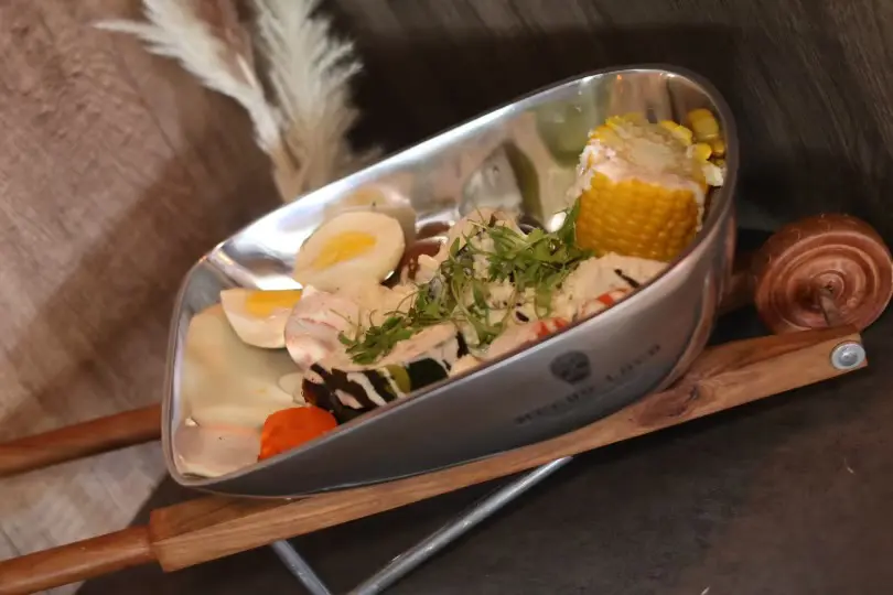 Salad with corn on the cob in a wheelbarrow.