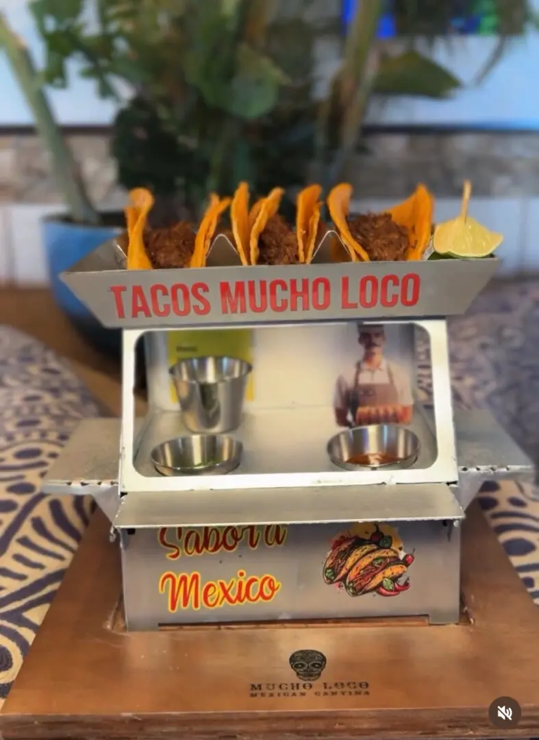 Miniature taco stand with tacos on top.