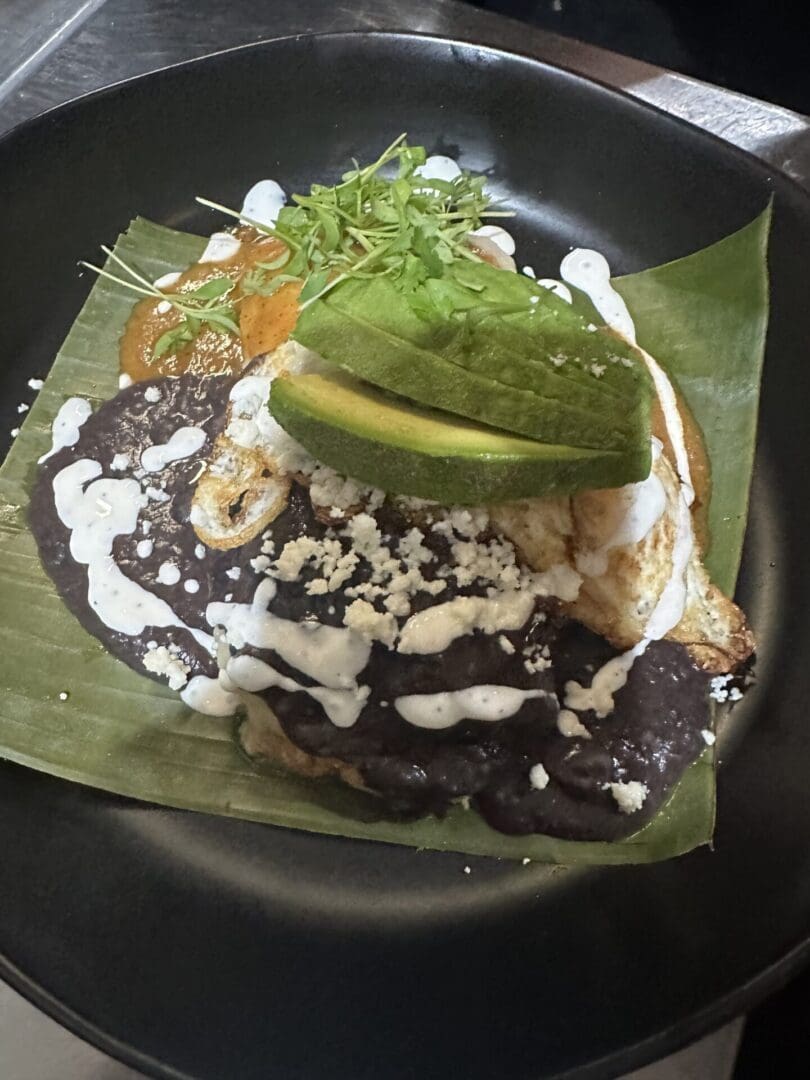 Black beans, avocado, and egg on a banana leaf.