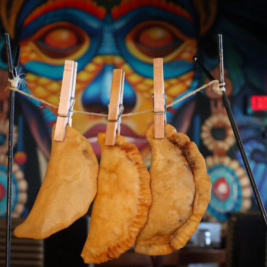 Three fried pastries hanging on clothespins.