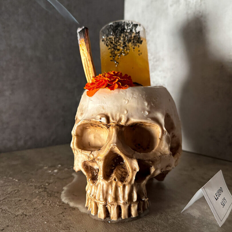 A skull with an orange candle and some other things in it