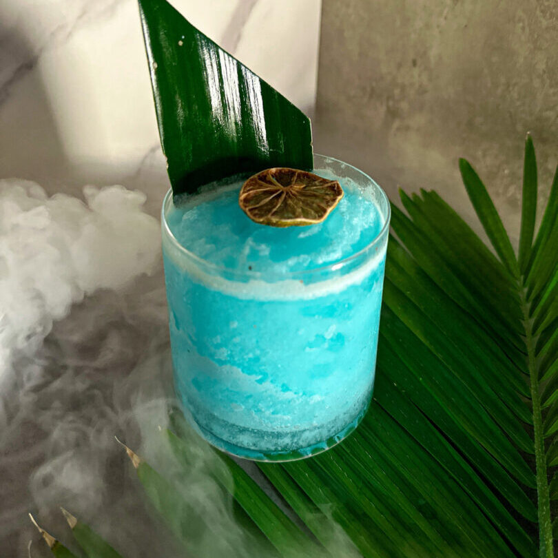 A blue drink with a leaf in it.